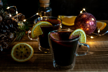 Christmas mulled wine with oranges and spices on wooden background.