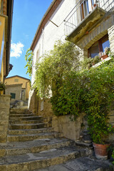 A small road crosses the old buildings of Catelmezzano, a rural village in the Basilicata region, Italy.
