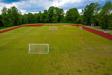 aerial view of empty green football field and red running tracks