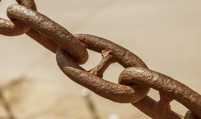 The old rusty metal chain of the anchor of the ship. Giant heavy steel chain leading from land to sea. Yellow mooring line of cargo ship. Ancient rusty Marine anchor chain