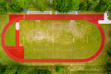aerial view of empty green football field and red running tracks