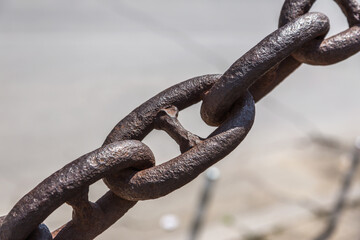 The old rusty metal chain of the anchor of the ship. Giant heavy steel chain leading from land to sea. Yellow mooring line of cargo ship. Ancient rusty Marine anchor chain