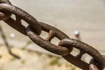 The old rusty metal chain of the anchor of the ship. Giant heavy steel chain leading from land to sea. Yellow mooring line of cargo ship. Ancient rusty Marine anchor chain
