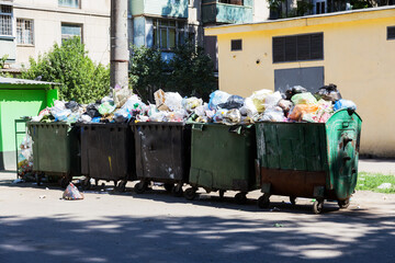 Overcrowded garbage containers with rubbish. Disused solid household garbage on road. Environmental pollution. Ecological problem. Abandoned garbage on road. Problem of waste management in a big city