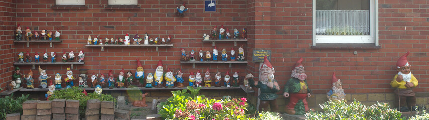 Viele Gartenzwerge an Hauswand rotes Haus Ziegelsteine