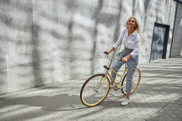 Naklejka premium Happy smiling Caucasian female in elegant casual clothes starting riding her bike