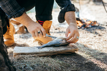 A man with a knife cuts fish in forest