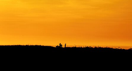 Family silhouette having fun on the beach at the sunset time. Concept of friendly family and of summer vacation.