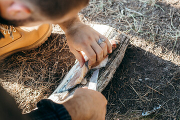 A man with a knife cuts fish in forest