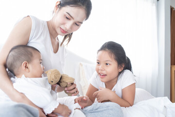 happy loving family. Love, trust and tenderness concept. Mother and child on a white bed. Parent and little kid relaxing at home. Mother and her daughters children girls playing and hugging.