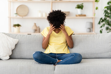 Unhappy Black Girl Touching Head Sitting On Couch At Home