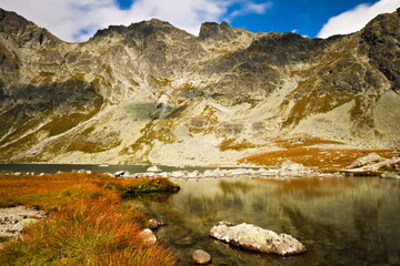 Mountain lake under the mountaintops  with a rock in the foreground