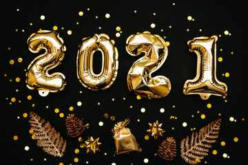 Gold numbers 2021 and next to them holiday items on a black or dark background. Christmas or New Year background.
