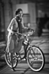 Fototapeta na wymiar Blurred image of woman on the bike, retro, skirt, street. Girl on bike, enjoy sunny autumn or spring day