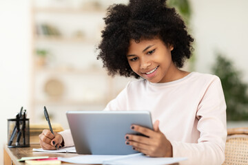 Black Teenager Girl Using Tablet Computer Learning Distantly At Home