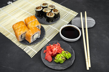 Fototapeta na wymiar philadelphia maki rolls and eel unagi maki with soy sauce, pink ginger, wasabi on black background, asian food, japanese sushi set