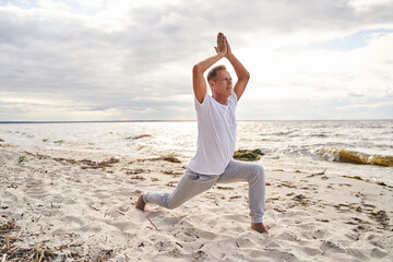 Serene man practicing yoga in morning in beach