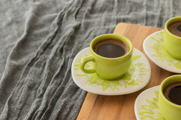 Turkish coffee standing on wooden piece. Gray cover in the background