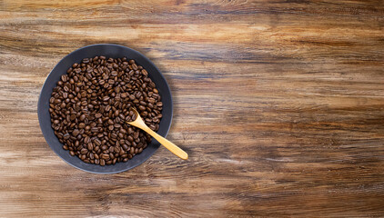 coffee beans in dark bowl cup on isolated wooden textured background