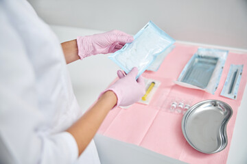 Doctor in latex gloves examining sterile gauze pads