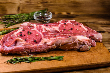 Raw ribeye steak, glass jar with spices and rosemary on cutting board