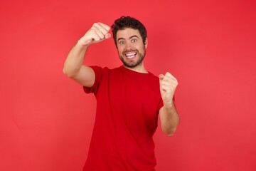 Young handsome caucasian man wearing t-shirt over isolated red background  imagine steering wheel...