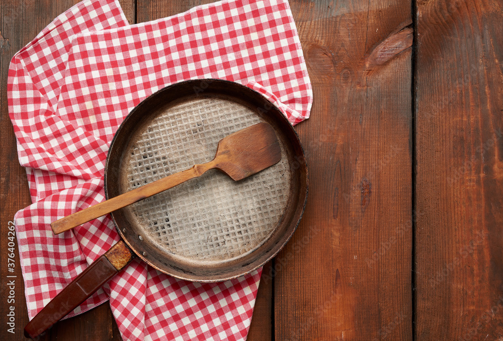 Poster empty round frying pan with handle on brown wooden table