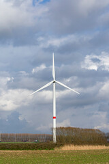 Fototapeta premium Wind turbine that provides electricity along the side of the road with threatening dark clouds in the background
