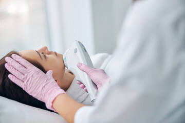 Naklejka premium Woman receiving an ultrasound facial in a beauty salon
