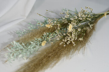 A bouquet of dried flowers close-up. Beige on a dark gray background.