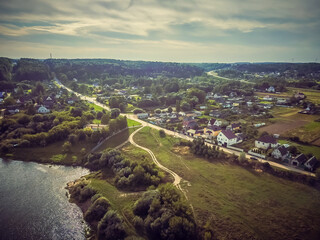 Village near the river, forests during the summer sunset, panoramic view from above by aerial drone