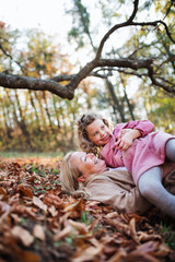 Small girl with grandmother on a walk in autumn forest, having fun.