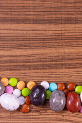 Colored eggs and colored chocolate tablets on exotic natural wood background