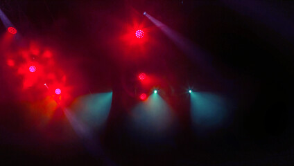 Stage lights. Several projectors in dark. A bright colored spotlight permeates the darkness. Light from the stage, rock concert. Lighting equipment. Several projectors on theatrical lighting system