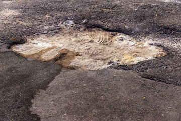 Damaged road, cracked asphalt sword with potholes and spots, Ukraine. Very bad asphalt road with large holes. Terrible technology construction roads. Numerous dangerous failures. Bad road