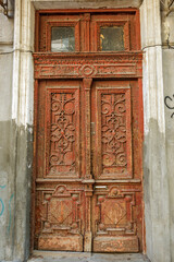 An old wooden painted antique front door. An old wooden front door with thick paint cracked in large cracks. Vintage wooden door on the facade of dilapidated building