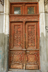 An old wooden painted antique front door. An old wooden front door with thick paint cracked in large cracks. Vintage wooden door on the facade of dilapidated building