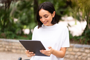 Fototapeta premium Young caucasian woman holding a tablet at outdoors