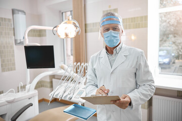 Qualified dentist looking at the screen of a tablet - obrazy, fototapety, plakaty