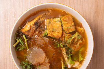 Thai red curry sour soup with deep fried fish fillet and fried egg