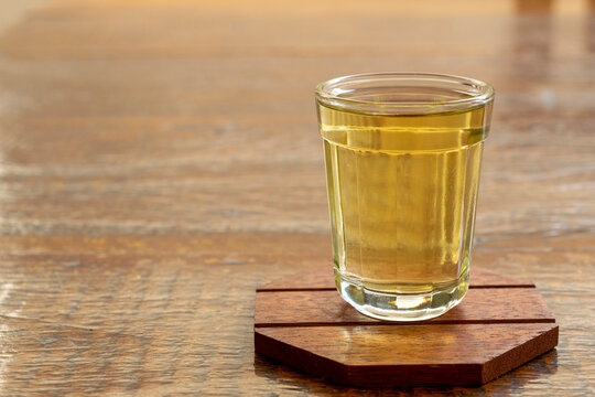 glass of golden cachaça on rustic table. Brazilian sugar cane drink. space for text