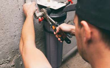 The plumber is repairing the water filter in the  basement