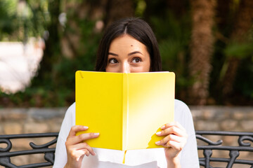 Fototapeta premium Young caucasian student woman holding notebooks at outdoors