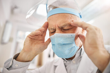 Fototapeta premium Elderly healthcare professional touching his head and frowning