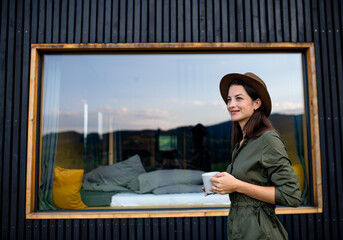 Young woman outdoors, weekend away in container house in countryside.