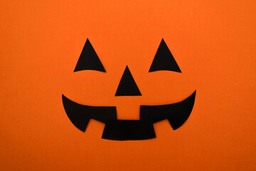 Black eyes,nose and mouth of black paper on an orange background.Halloween concept.