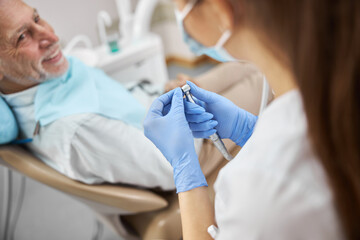 Young dentist starting a dental drill at clinic