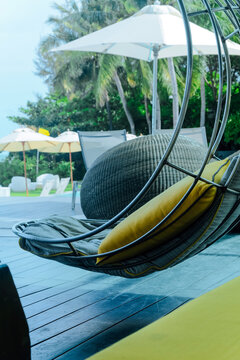 Image of Relaxing chairs with pillows beside swimming pool