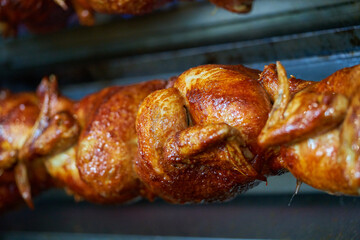 Rows of hot roasted skewered whole rotisserie chickens, in Spain