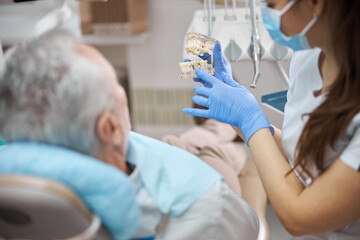 Qualified female dental technician holding dental prosthetics